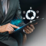 Businessman using digital tablet to manage operations with futuristic facility management icons, representing automation, analytics, and workflow optimization.